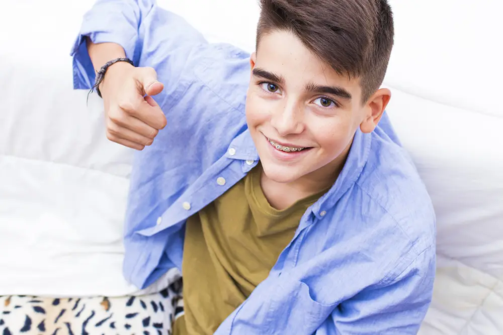 Beverly Hills Boy with headphones at a skatepark smiling after getting traditional metal braces for teens 